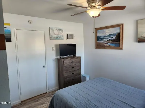 a bedroom with a bed and a flat tv screen on dresser