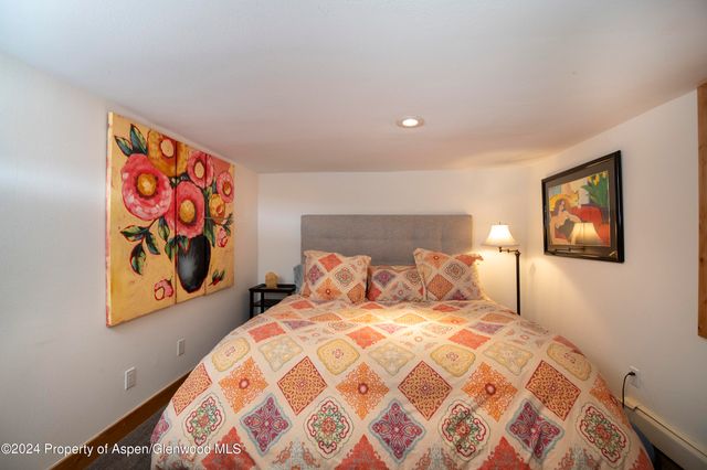 a bedroom with a bed and painting on the wall