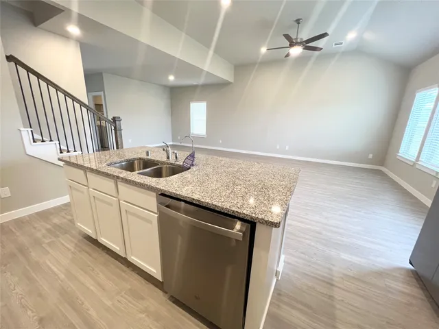 a kitchen with granite countertop a sink and dishwasher with wooden floor