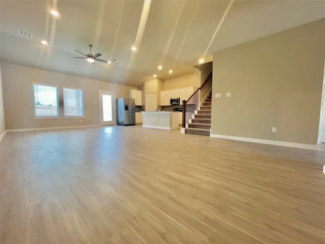 an empty room with wooden floor and stairs