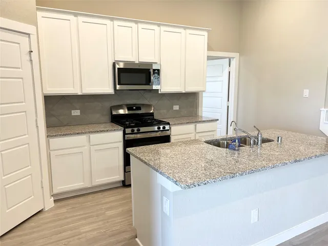 a kitchen with granite countertop a sink stove and microwave