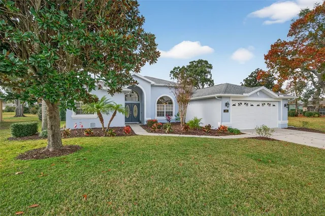 a front view of a house with a garden and trees