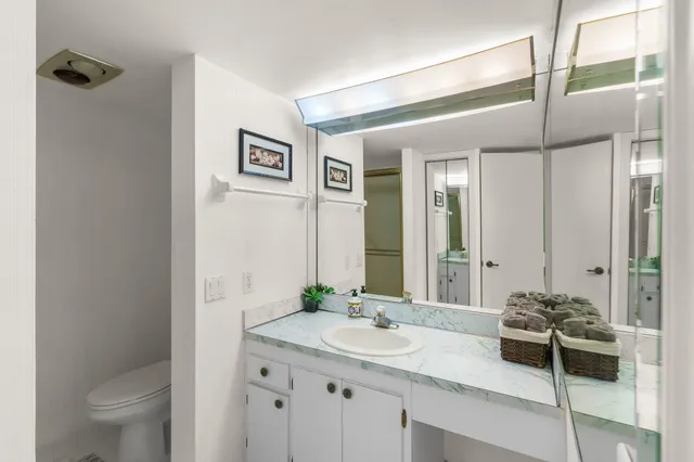 a bathroom with a granite countertop sink a toilet and a mirror
