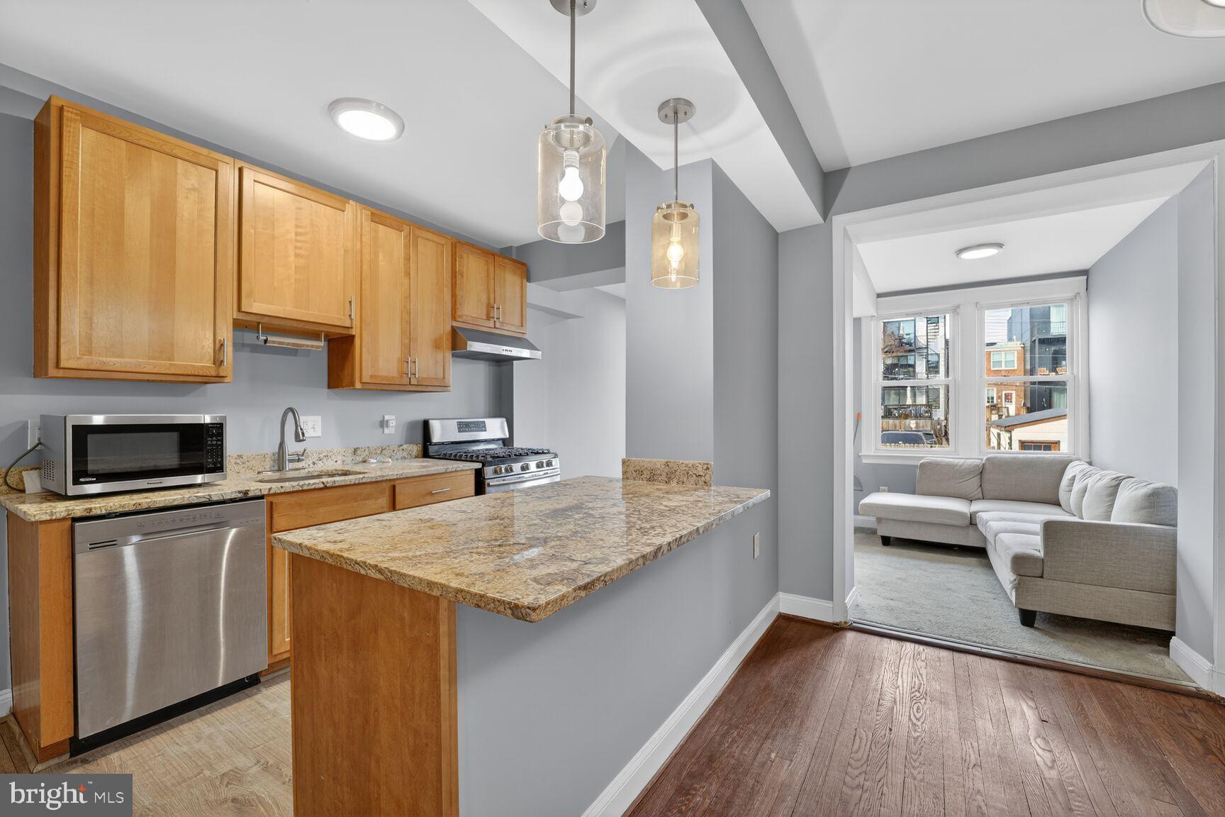 a kitchen with a sink dishwasher a stove and white cabinets with wooden floor