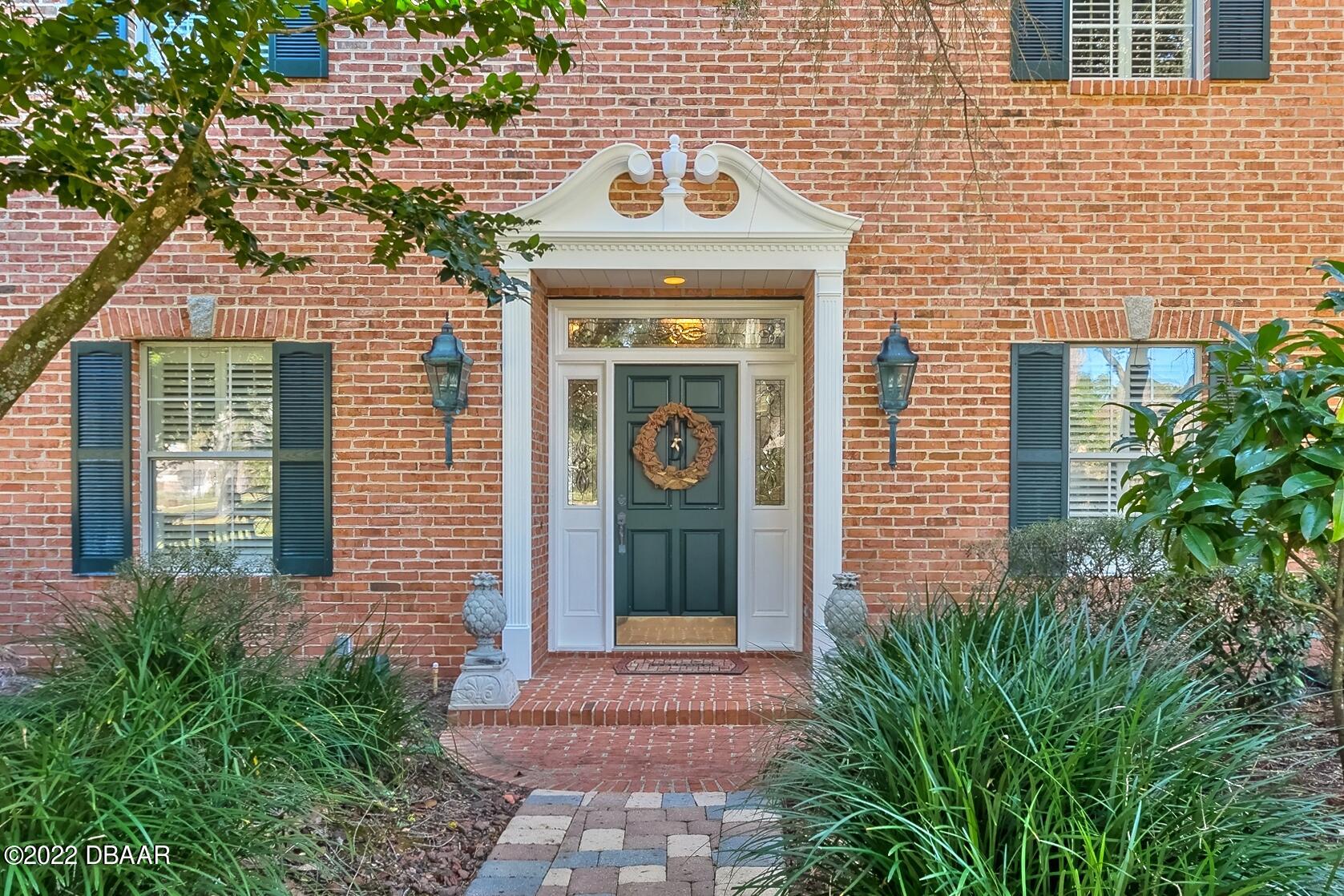 8 Moss Point Drive Ormond Beach, FL 32174 - Photo 12 of 63 a view of a brick house with potted plants