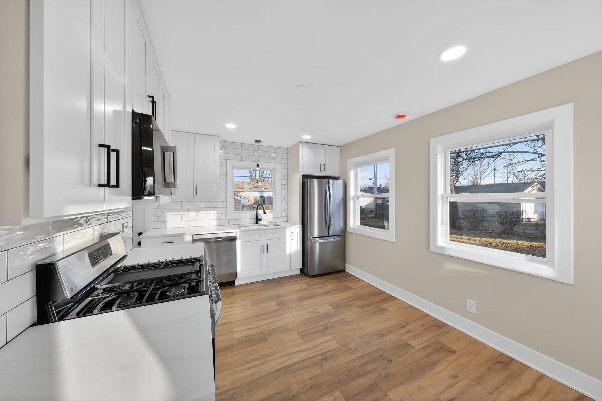 423 Cline Avenue Griffith, IN 46319 - Photo 5 of 33 a kitchen with stainless steel appliances a stove a sink cabinets and a wooden floor
