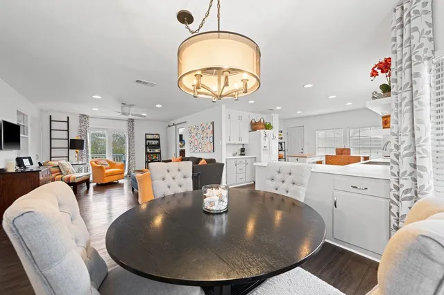 a kitchen with stainless steel appliances a stove a sink a refrigerator white cabinets and wooden floor