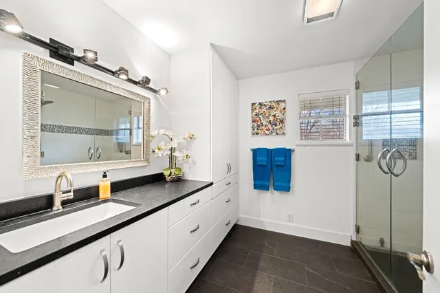 a bathroom with a granite countertop shower a sink and a window
