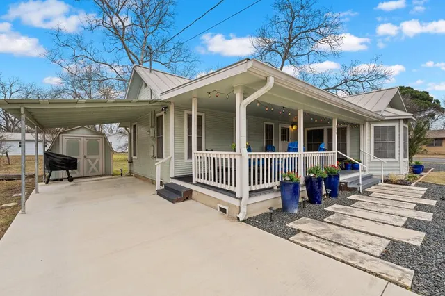 a view of a house with a wooden deck and a large tree