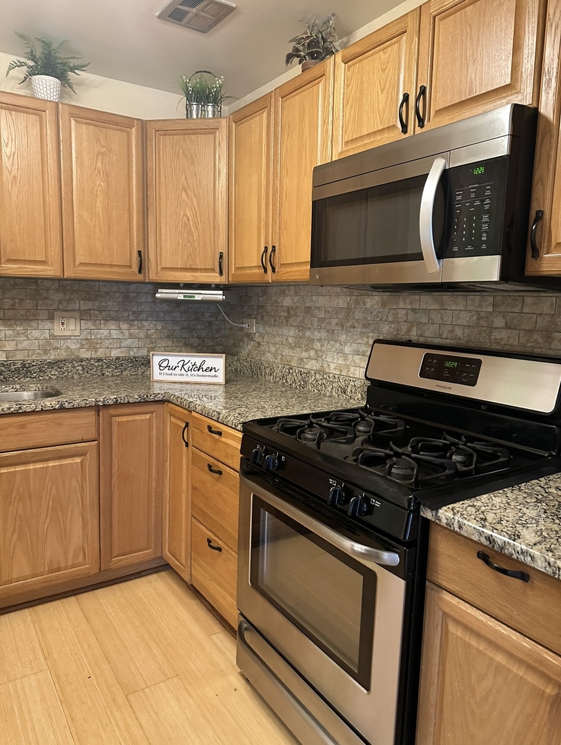 9s070 South Frontage Road, Unit 204 Willowbrook, IL 60527 - Photo 2 of 18 a kitchen with granite countertop a stove top oven cabinetry a sink and a window