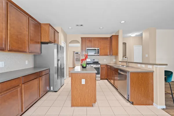 a kitchen with stainless steel appliances granite countertop a refrigerator a stove and a sink