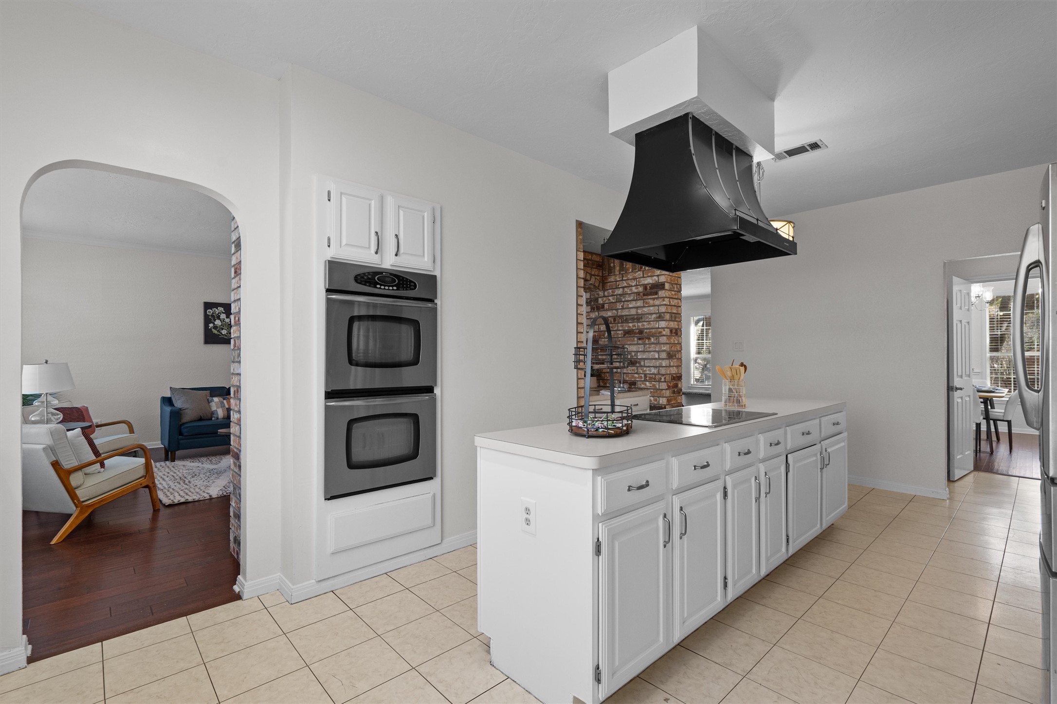 10506 Walpole Lane Austin, TX 78739 - Photo 14 of 40 Kitchen with light tile patterned floors, white cabinets, arched walkways, stainless steel appliances, and light countertops