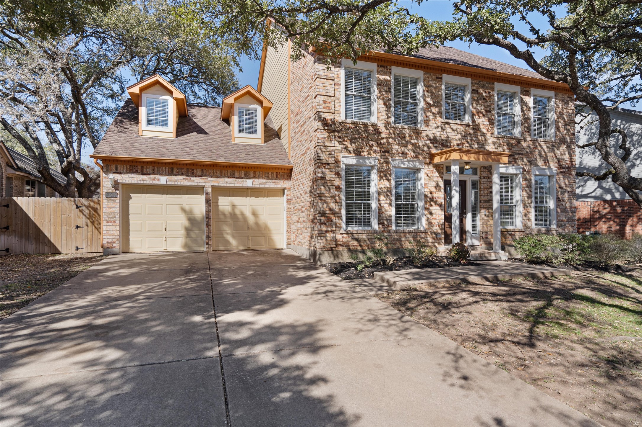 10506 Walpole Lane Austin, TX 78739 - Photo 2 of 40 Colonial inspired home featuring concrete driveway, a gate, roof with shingles, an attached garage, and brick siding