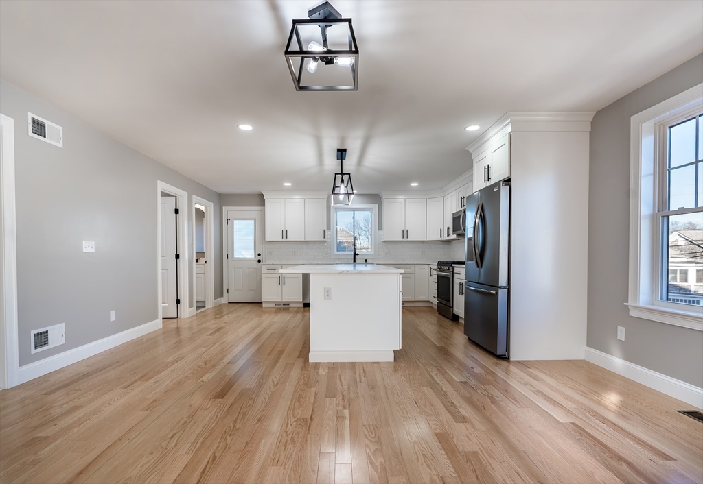 214 Horton Street Fall River, MA 02723 - Photo 5 of 40 a large kitchen with stainless steel appliances kitchen island a large counter top and wooden floor