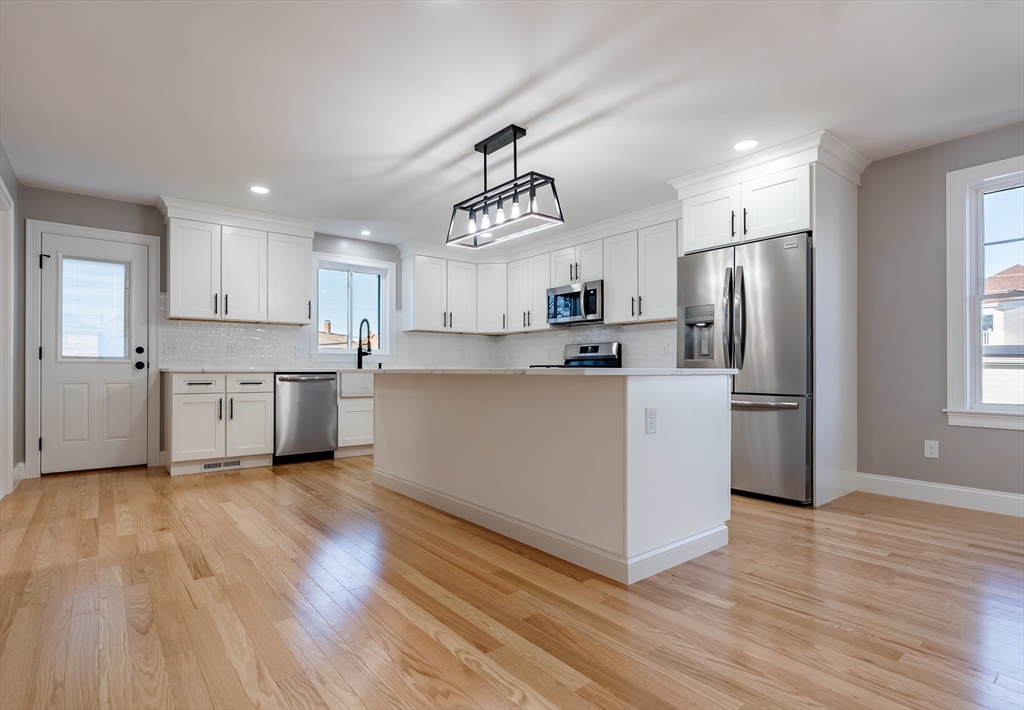 214 Horton Street Fall River, MA 02723 - Photo 9 of 40 a kitchen with wooden floors white cabinets and stainless steel appliances