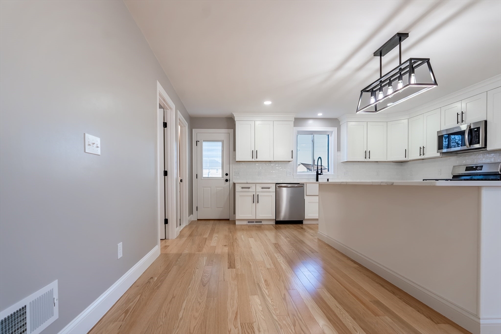 214 Horton Street Fall River, MA 02723 - Photo 10 of 40 a kitchen with stainless steel appliances granite countertop a refrigerator a sink dishwasher a stove and white cabinets with wooden floor