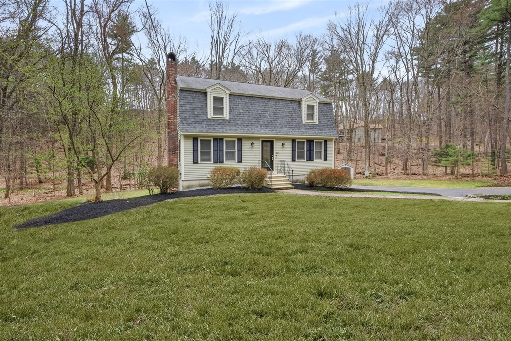 a front view of a house with garden and trees