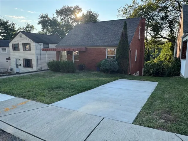a front view of a house with a yard and trees