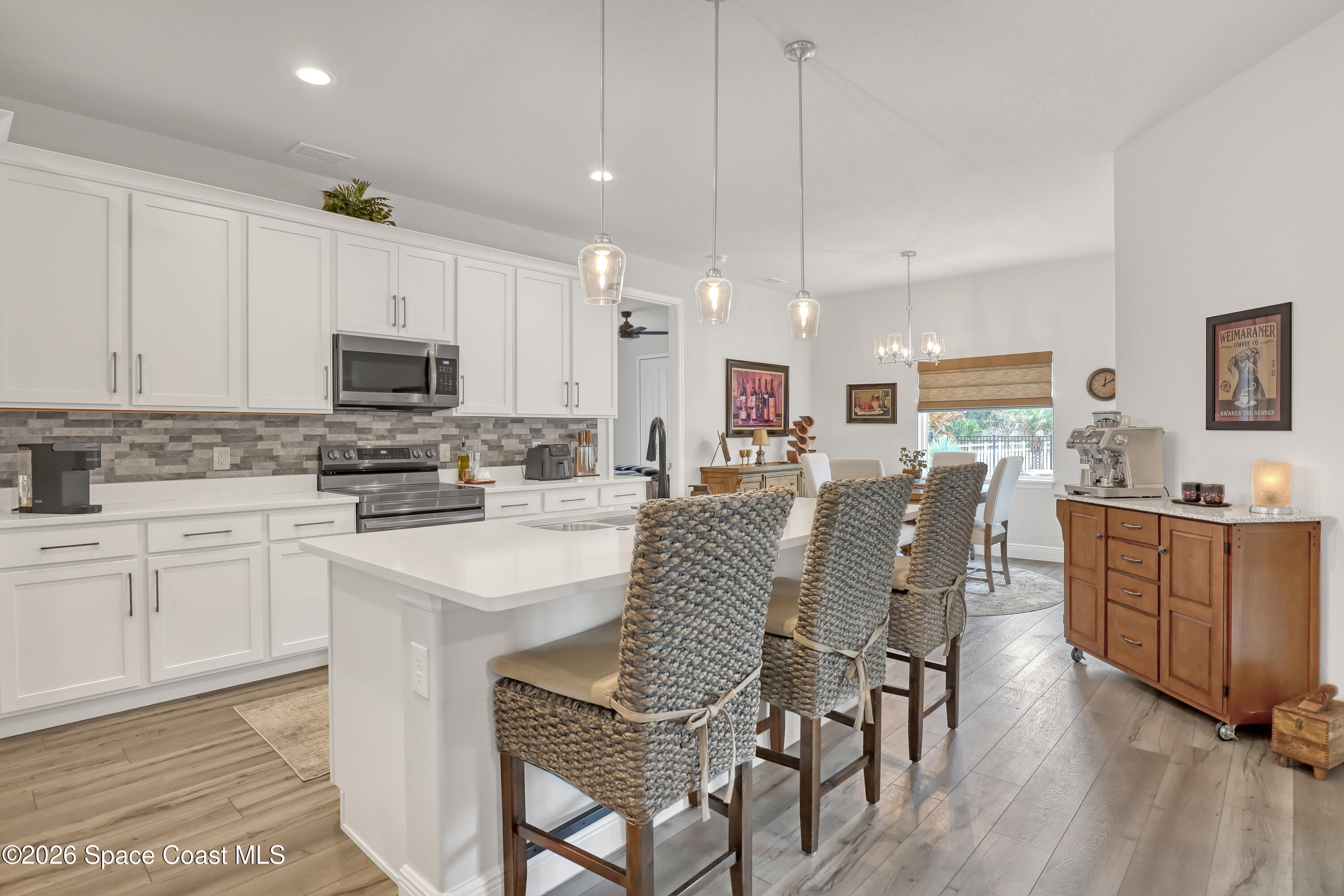 1837 Market Circle Northeast Palm Bay, FL 32905 - Photo 8 of 57 a kitchen with stainless steel appliances kitchen island granite countertop a table chairs and a refrigerator