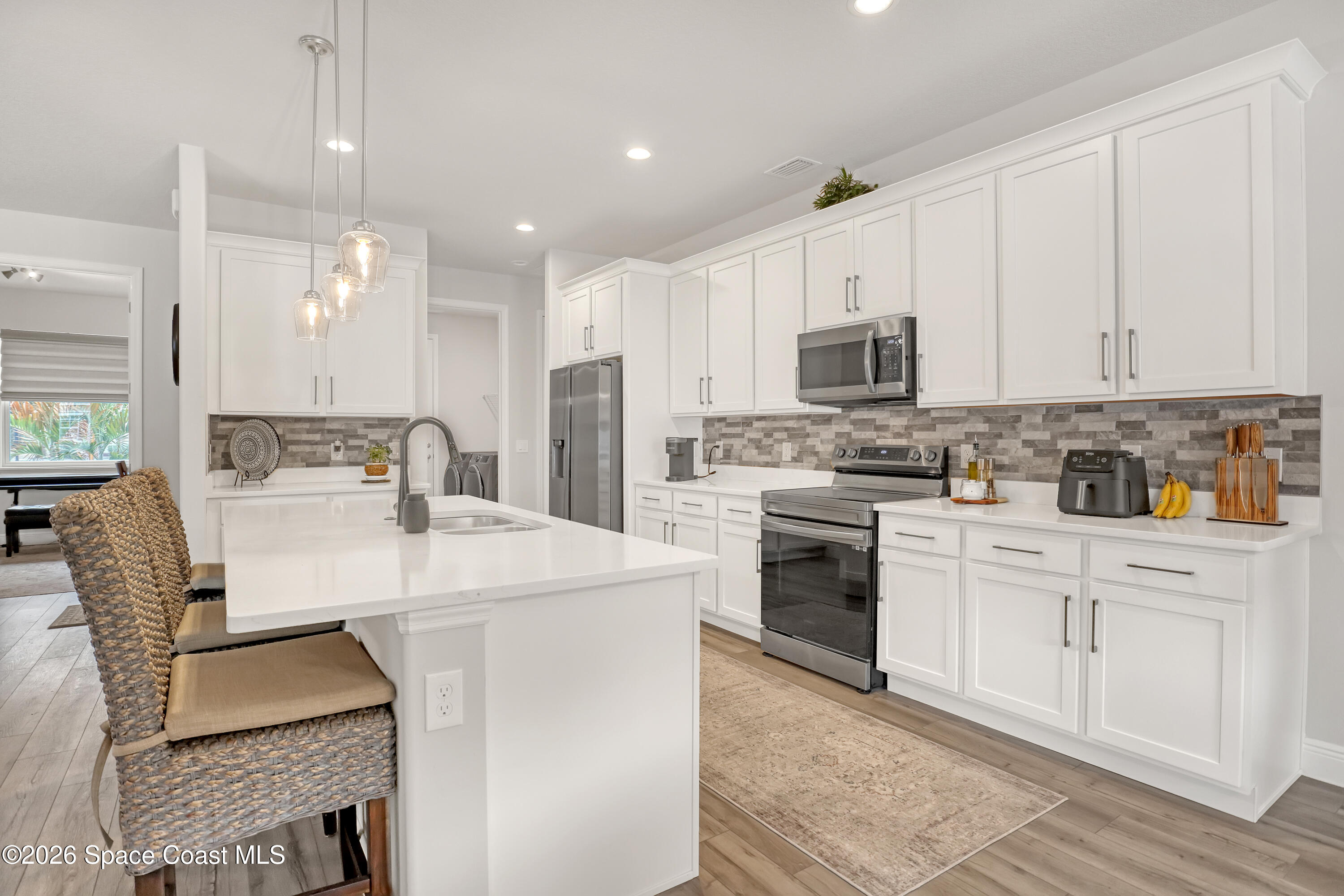 1837 Market Circle Northeast Palm Bay, FL 32905 - Photo 9 of 57 a kitchen with kitchen island granite countertop a stove a sink a refrigerator and white cabinets with wooden floor