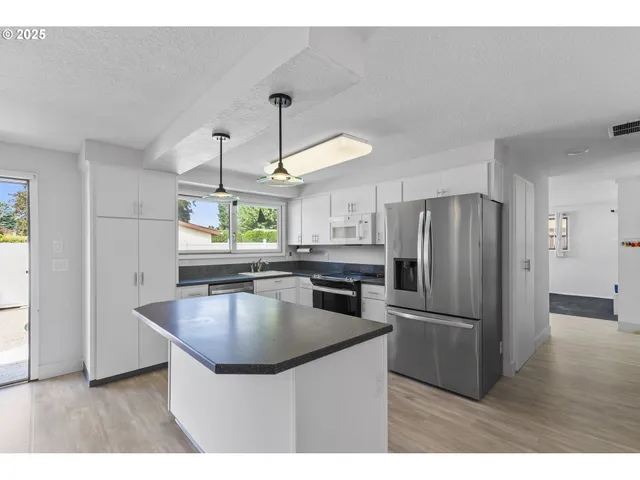 a kitchen with kitchen island a counter top space appliances and a ceiling fan