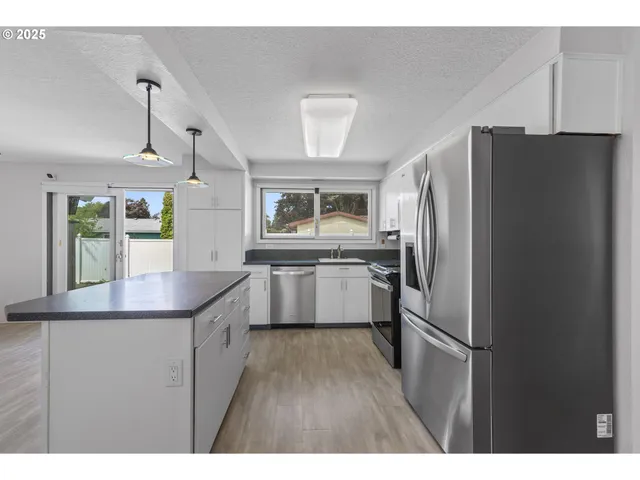 a kitchen with kitchen island a counter top space a sink appliances and cabinets