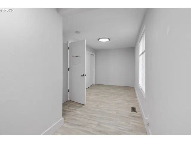 a view of an empty room with window and wooden floor