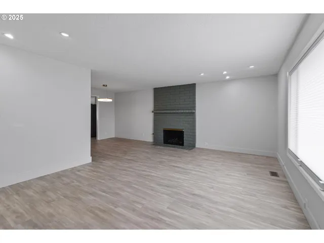 a view of empty room with wooden floor and fireplace