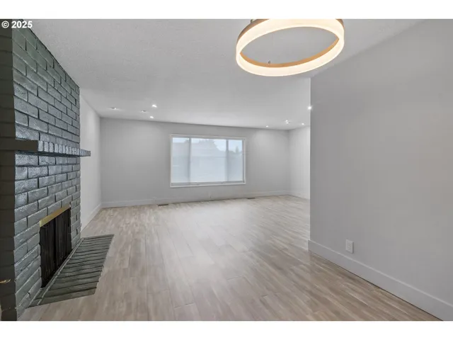 a view of an empty room with a fireplace and a window