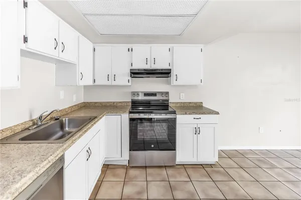 a kitchen with granite countertop a stove sink and cabinets