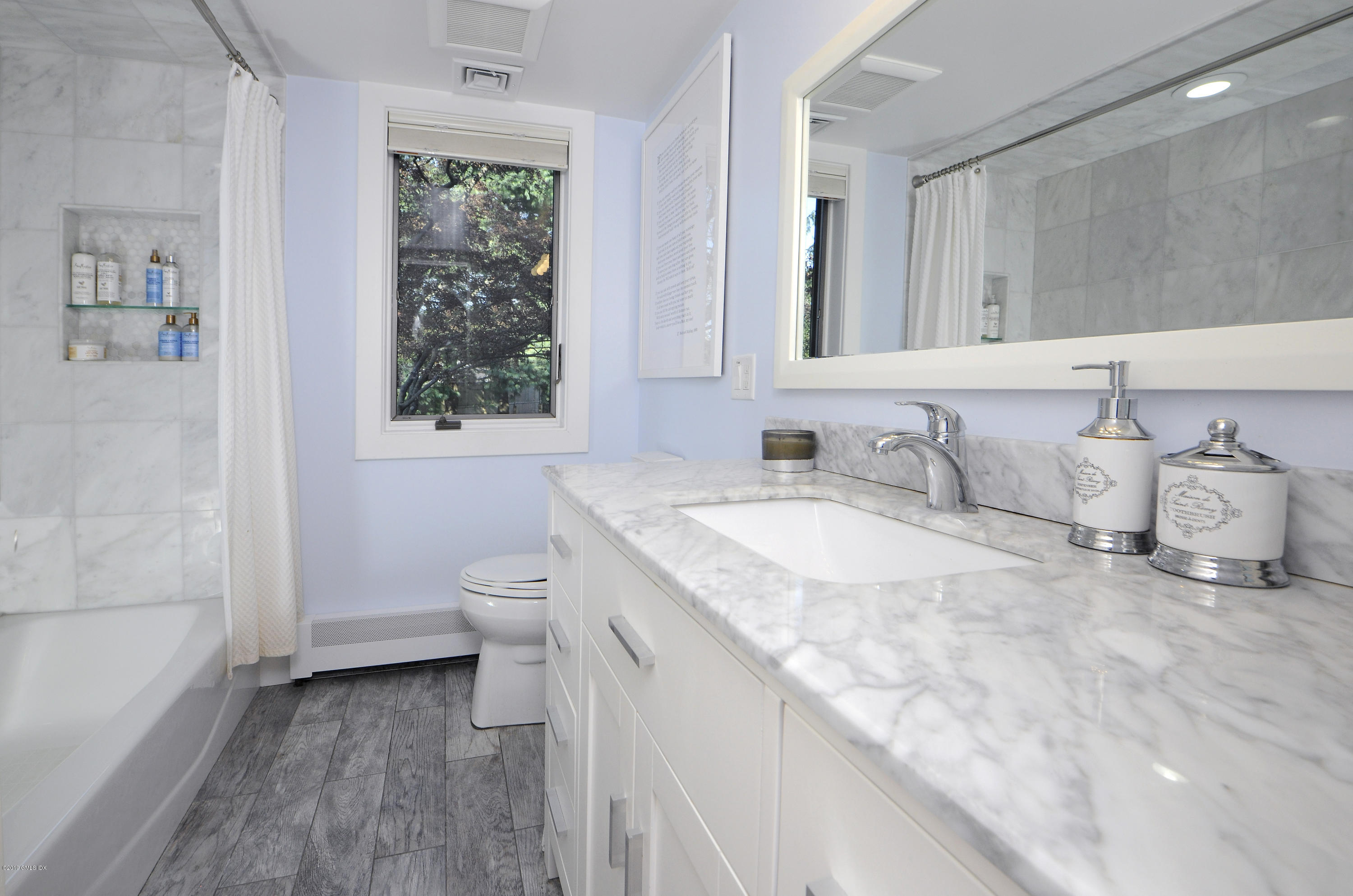 249 Shore Road Greenwich, CT 06830 - Photo 17 of 24 a bathroom with a granite countertop sink a toilet and a large mirror