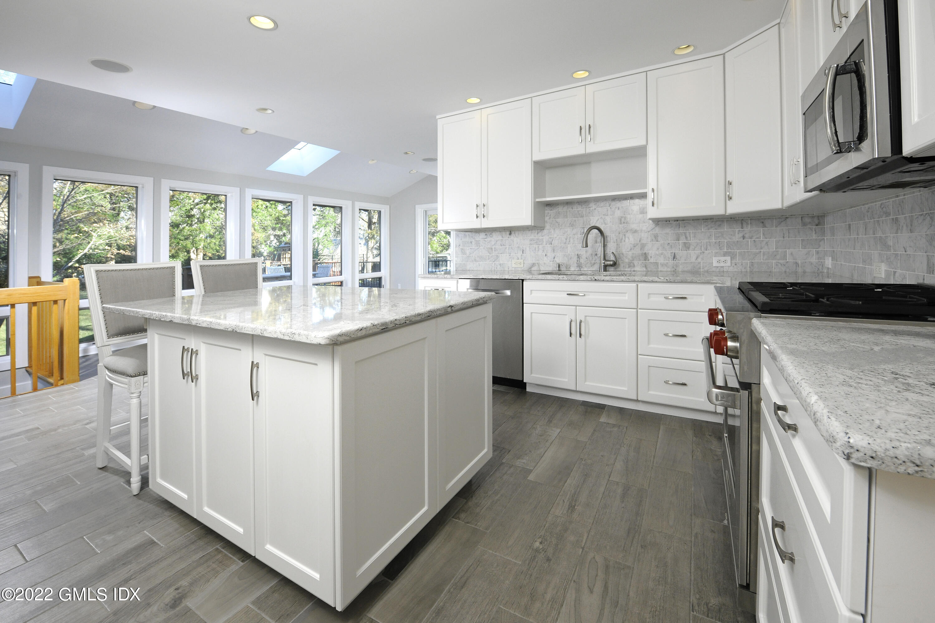 249 Shore Road Greenwich, CT 06830 - Photo 4 of 24 a kitchen with granite countertop white cabinets white appliances a sink and a large window