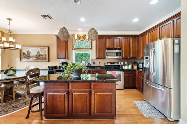 a kitchen with stainless steel appliances granite countertop a stove a sink dishwasher and a microwave oven with cabinets