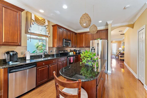 a kitchen with granite countertop a stove a sink dishwasher and cabinets with wooden floor
