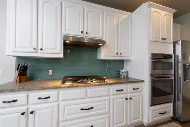 a kitchen with white cabinets and appliances