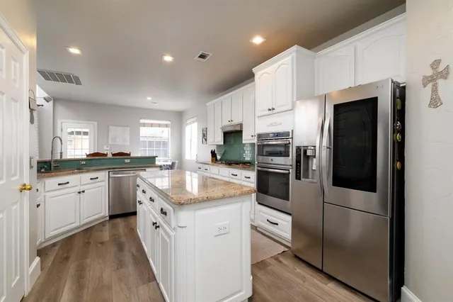 a kitchen with white cabinets and stainless steel appliances