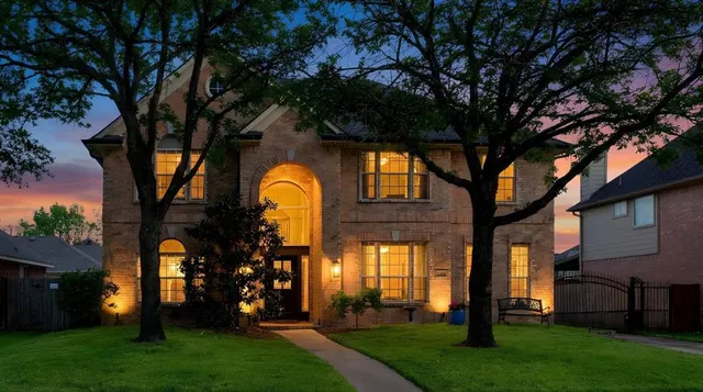 a front view of a house with garden and trees