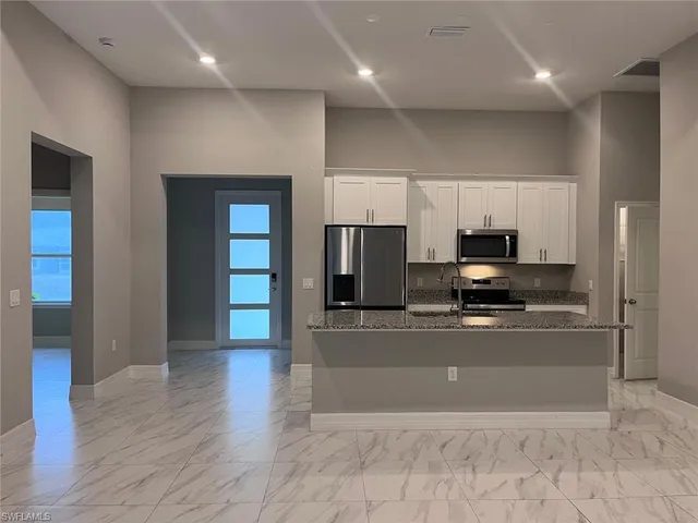 a large kitchen with stainless steel appliances a refrigerator and a stove top oven