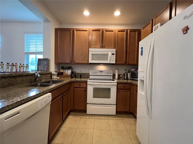 a kitchen with granite countertop a refrigerator stove top oven and sink
