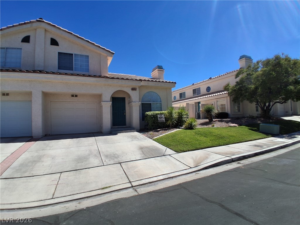 8023 Simone Avenue Las Vegas, NV 89147 - Photo 1 of 12 A cream-colored stucco home features a two-car garage and a neatly maintained lawn.