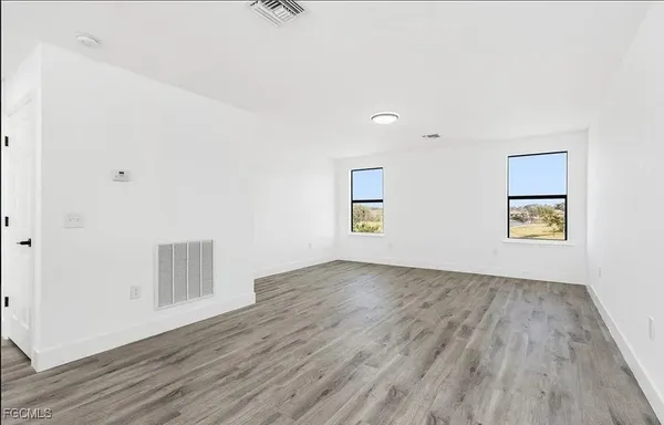 an empty room with a window and wooden floor