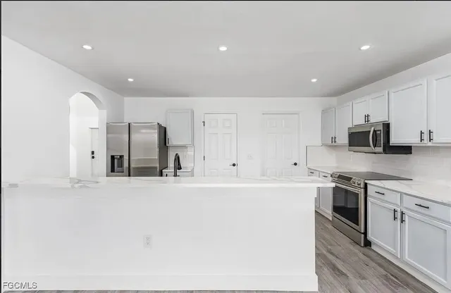 a large kitchen with stainless steel appliances granite countertop a stove a sink and a refrigerator