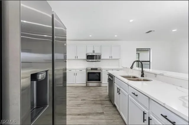 a kitchen with stainless steel appliances granite countertop a sink and a refrigerator