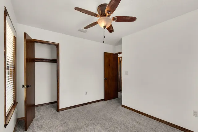 an empty room with closet and ceiling fan
