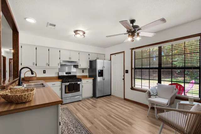 a kitchen with stainless steel appliances granite countertop a stove top oven a sink dishwasher a dining table and chairs with wooden floor