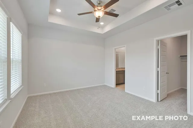 an empty room with windows and ceiling fan