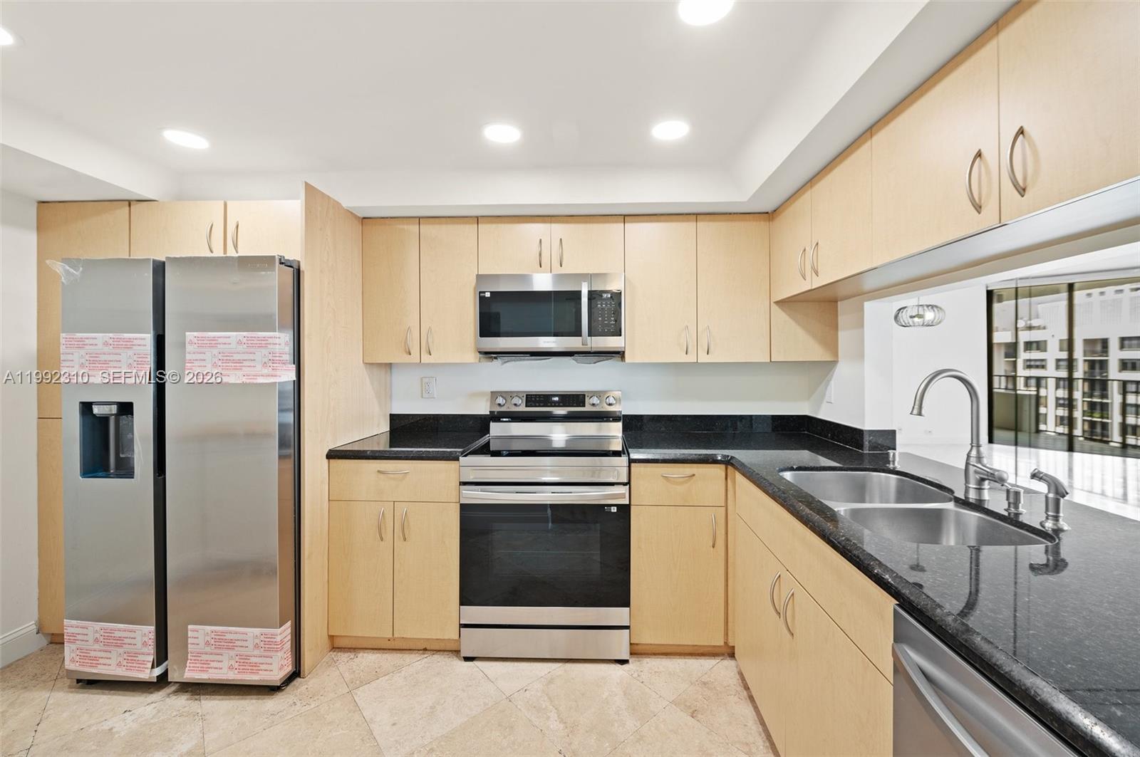 520 Brickell Key Drive, Unit A1712 Miami, FL 33131 - Photo 11 of 34 a kitchen with granite countertop a sink stainless steel appliances and cabinets