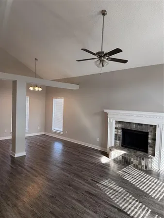 a view of an empty room with wooden floor fireplace and a window
