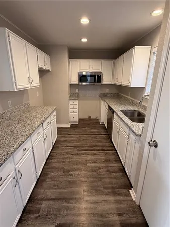 a large kitchen with granite countertop lots of counter top space and stainless steel appliances