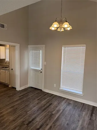 an empty room with wooden floor cabinet and windows